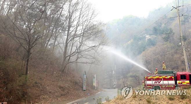 민가로 다가오는 대전 산불 저지하는 소방 당국 (대전=연합뉴스) 강수환 기자 = 대전 서구 산직동에서 발생한 산불이 사흘째 이어지는 4일 오전, 안평산의 불길이 장안저수지 인근 민가까지 확대하는 것을 막기 위해 진화 작업이 투입된 동부소방서 대원들이 물을 뿌리고 있다. 2023.4.4 swan@yna.co.kr