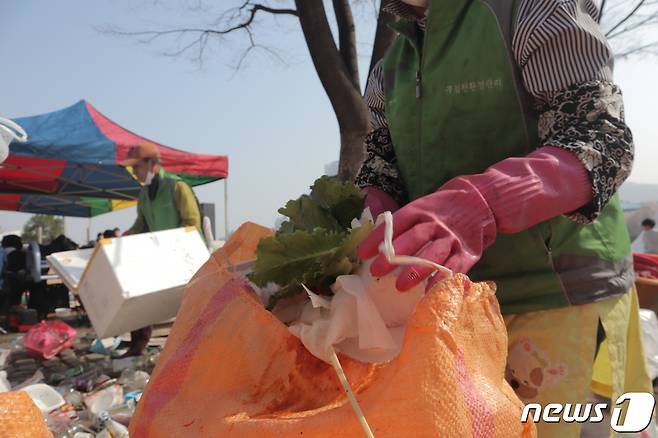 '1회 벚꽃과 함께하는 푸드트럭 축제' 개막 다음 날인 지난 1일 충북 청주시 무심천체육공에서 환경관리원들이 전날 밤 발생한 쓰레기를 치우고 있다.2023.4.1/ⓒ 뉴스1 박건영 기자