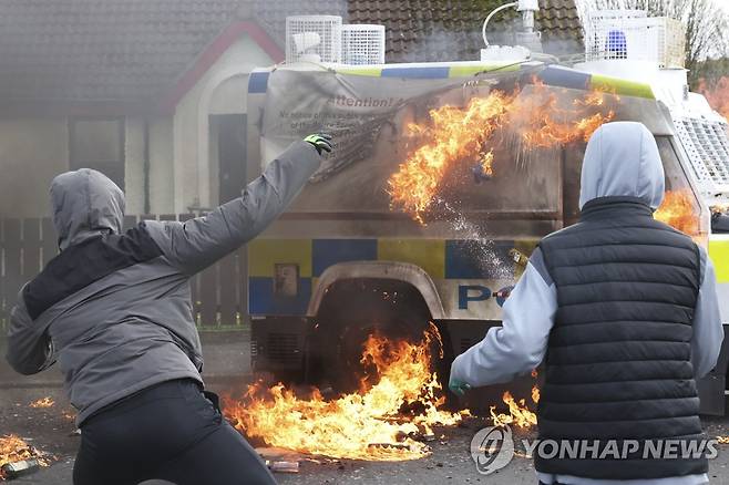 북아일랜드서 경찰차에 화염병 던지는 아일랜드 민족주의자들 (AP=연합뉴스) 북아일랜드 런던데리에서 10일(현지시간) 마스크를 쓴 청년들이 경찰차에 화염병을 던지고 있다. 이날 벨파스트(성금요일) 평화협정에 반대하는 아일랜드 민족주의자들이 전투복 같은 옷을 입고 미신고 거리 행진을 벌였다. 2023.4.10 photo@yna.co.kr