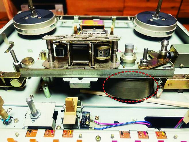 녹아내린 캡스턴 벨트 교체를 위해 분해한 타스캄 34B 내부. 녹음재생 헤드 아래쪽 검은 쇠 뭉치(점선 표시)가 캡스턴에 회전력을 전하는 휠이다.