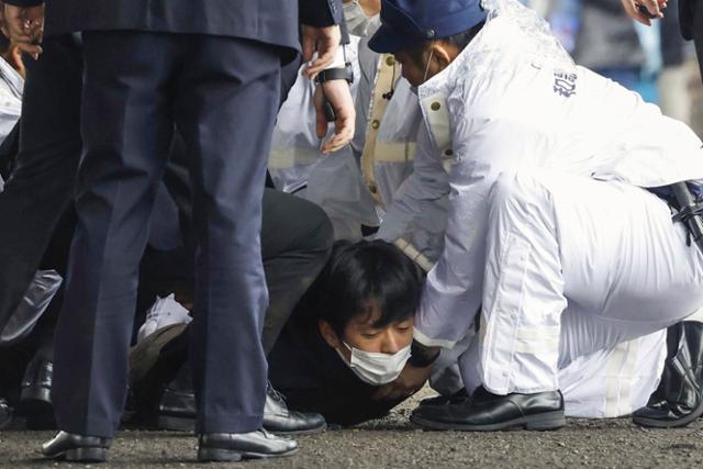 15일 보궐선거 여당 후보 지원을 위해 일본 와카야마현의 항구를 찾은 기시다 후미오 일본 총리가 연설하기 직전 폭발물을 던진 것으로 보이는 용의자가 체포되고 있다. 와카야마=AP 뉴시스