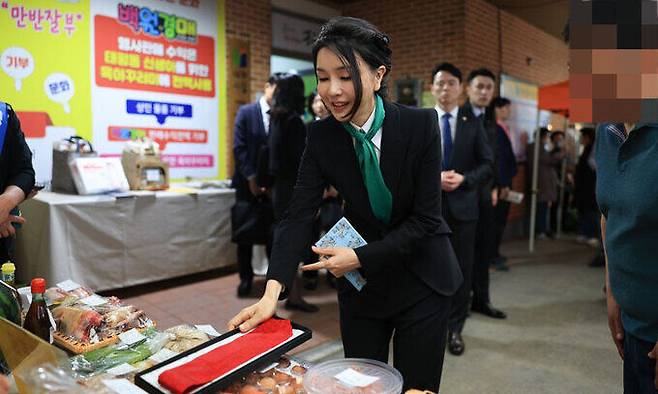 김건희 여사가 14일 대전 중구 태평전통시장을 방문해 윤석열 대통령이 착용했던 넥타이를 100원 경매에 기부하고 있다. 대통령실 제공