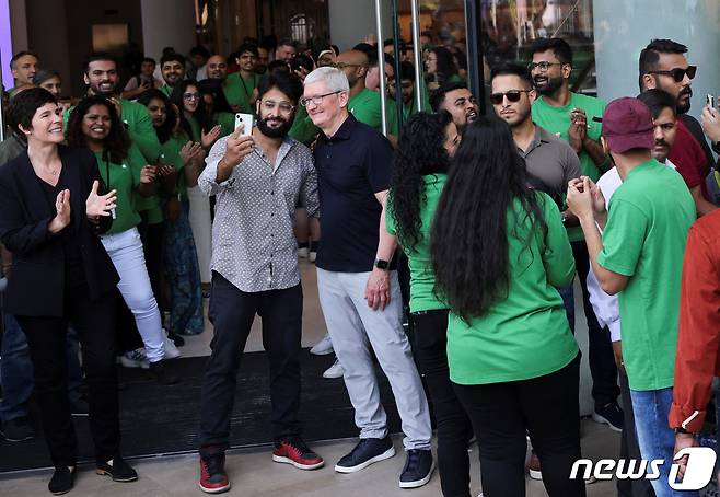 18일 뭄바이에서 열린 인도 첫 애플스토어 개장식에서 한 남성이 팀 쿡 애플 최고경영자(CEO)와 함께 사진을 찍고 있다. 2023.04.18/뉴스1 ⓒ 로이터=뉴스1 ⓒ News1 김민수 기자