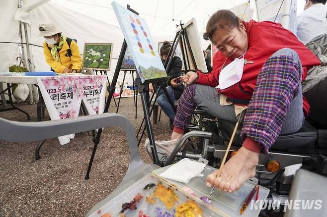 제43회 장애인의 날을 이틀 앞둔 18일 오전 서울 영등포구 여의도공원 문화의마당에서 열린 '2023 동행서울 누리축제'에서 구족화가 김경아씨가 그림을 그리고 있다.