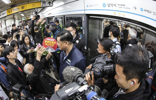 박경석 전국장애인차별철폐연대 상임대표와 회원들이 20일 서울 용산구 지하철 4호선 삼각지역에서 장애인의 날을 맞아 출근길 지하철 탑승시위 도중 꽃을 던지고 있다. 뉴시스