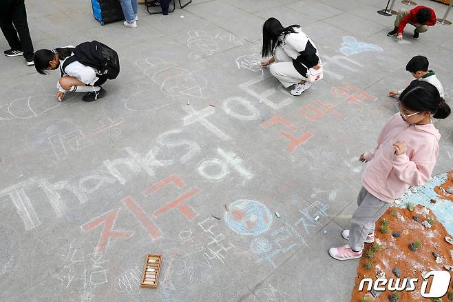 22일 서울 종로구 광화문광장에서 지구의 날을 맞아 열린 '2023 지구의 날 행사'를 찾은 어린이들이 분필로 바닥에 환경보호 메시지를 적고 있다. 2023.4.22/뉴스1 ⓒ News1 민경석 기자