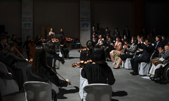 장애인의 날을 맞아 김건희 여사가 20일 인천 남동구 특수학교 미추홀학교를 방문, 학생과 손을 마주치며 인사하고 있다.(위) 같은날 김 여사가 서울 청와대 춘추관에서 열린 ‘하트 시각장애인 체임버 오케스트라’ 특별공연에서 시각장애인의 연주 환경을 청중과 공유할 수 있도록 준비한 암전공연이 끝난 뒤 박수치고 있다. (아래) 연합뉴스