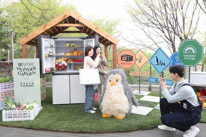 24일 남산서울타워에서 진행되는 ‘2023 얼루어 그린 캠페인’에 마련된 삼성전자 전시관에서 방문객들이 비스포크 냉장고와 펭귄 그로브몬스터, 김은하 작가의 업사이클링 작품과 함께 인증샷을 남기는 모습. [삼성전자 제공]