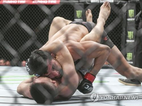 지난 2019년 UFC 부산 대회에서 리우핑위안을 누르는 강경호(사진 위) [연합뉴스 자료사진]