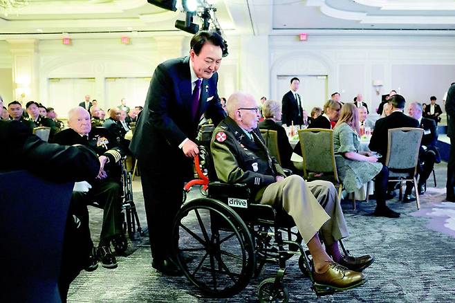 윤석열 대통령이 25일(현지 시간) 미국 워싱턴의 한 호텔에서 열린 한미동맹 70주년 기념 오찬에서 랠프 퍼킷 예비역 육군 대령의
 휠체어를 직접 밀며 무대로 이동하고 있다. 올해로 96세인 퍼킷 대령은 6·25전쟁 당시 수류탄에 맞고도 작전을 지휘하며 
평안북도 소재 205고지 진지를 6회나 사수하면서 대원들의 목숨을 구했다. 워싱턴=뉴시스