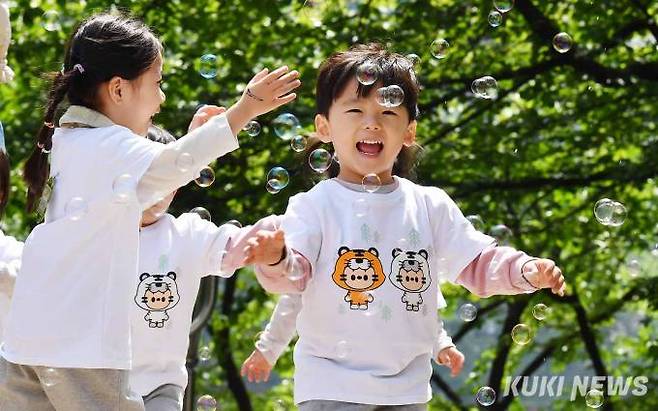 송파구 어린이날 큰잔치에 참여한 어린이들이 비눗방울을 손으로 터뜨리며 환하게 웃고 있다.