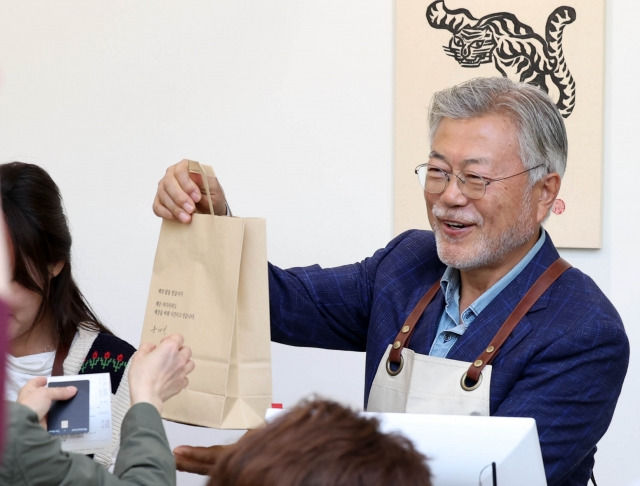 문재인 전 대통령이 26일 오후 경남 양산시 하북면 자신의 책방 '평산책방'에서 계산 업무를 하며 책을 손님에게 건네고 있다. 연합뉴스