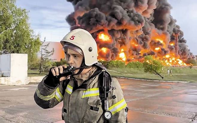 지난달 29일(현지 시각) 러시아가 점령 중인 우크라이나 크림반도 세바스토폴시의 유류 저장고에서 화염이 치솟는 가운데 소방관이 무전기에 대고 말하고 있다. 러시아 측은 “우크라이나 드론(무인기)의 소행”이라며 “인명 피해는 없다”고 밝혔다. /EPA 연합뉴스