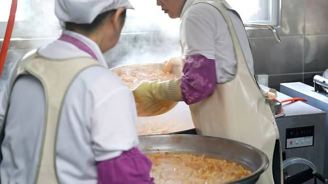 조리실무사들이 배식을 하기 위해 만들어진 음식을 옮기고 있다.