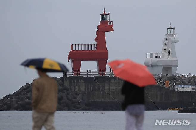 [제주=뉴시스] 우장호 기자 = 비가 내리기 시작한 3일 오후 제주시 이호해변에 우산을 쓴 관광객들이 지나가고 있다. 기상청에 따르면 이날 제주를 시작으로 오는 6일 오전까지 전국에 굵은 빗줄기가 쏟아질 것으로 전망된다. 2023.05.03. woo1223@newsis.com