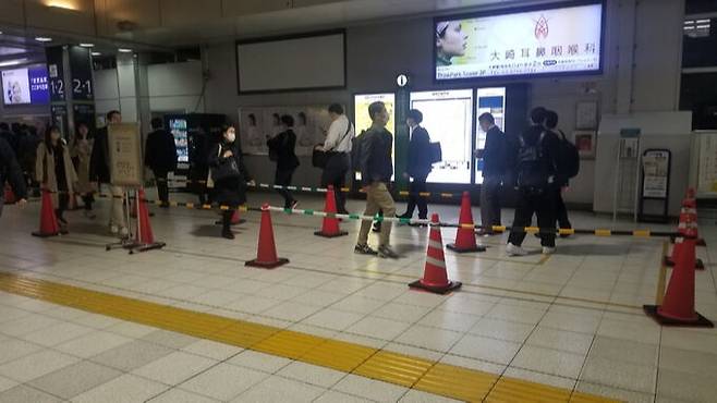 일본 도쿄 오사키역에서 지난 4월 24일 퇴근한 시민들이 가로분리봉을 따라 한 줄로 플랫폼으로 향하고 있다. 이 역에서는 승객이 한꺼번에 몰려 병목현상이 벌어지는 것을 막기 위해 퇴근 시간대에는 가로분리봉을 설치해 시민 이동을 유도하고 있다. 도쿄=강구열 특파원