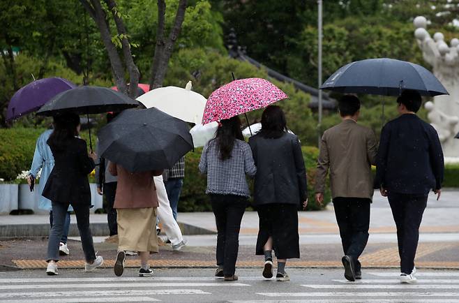 어린이날 연휴를 하루 앞둔 4일 광주 북구청 네거리에서 시민들이 우산을 쓰고 길을 걷고 있다. [연합]