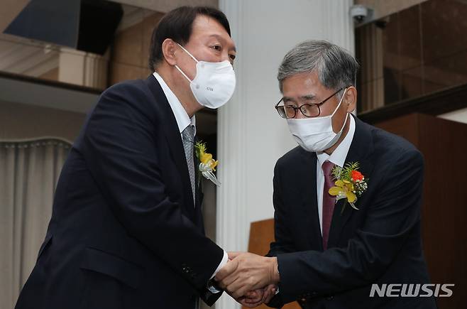 [서울=뉴시스] 국회사진기자단 = 윤석열 당시 국민의힘 대선 후보가 지난 2021년 11월9일 서울 중구 프레스센터에서 열린 신평 변호사 출판기념회에서 신 변호사와 악수하고 있다. 2021.11.09. photo@newsis.com