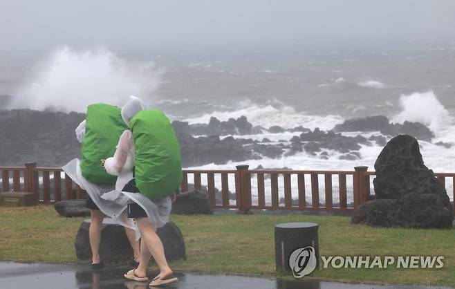 비바람 몰아치는 제주 해안 (서귀포=연합뉴스) 박지호 기자 = 제주에 호우특보가 내려진 4일 오전 제주 서귀포시 사계해안도로에서 우비로 무장한 배낭여행객이 걷고 있다. 2023.5.4 jihopark@yna.co.kr