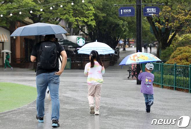 어린이날인 5일 대구 달서구 이월드를 찾은 가족이 우산을 쓴 채 정상 운행하는 놀이기구를 찾아 발걸음을 옮기고 있다. 이월드 측은 이날 많은 비가 내리자 안전상의 이유로 야외 놀이기구 운행을 대부분 중단하고, 어린이날 이벤트를 연기했다. 2023.5.5/뉴스1 ⓒ News1 공정식 기자