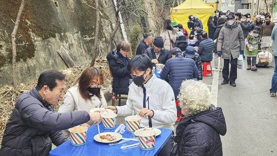 지난 2월 오후 대구 북구 대현동 경북대학교 서문 인근 골목가에서 돼지고기 수육과 소고기국밥을 받은 사람들이 식사를 하고 있다. 이날 돼지고기 잔치는 이슬람 사원 건립을 반대하는 대현동 주민 중 일부가 주최했다. 중앙포토