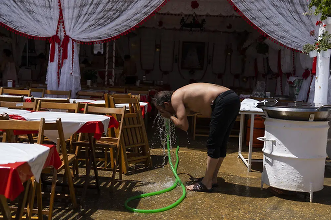 스페인 세비야에서 열린 연례 4월 박람회에서 한 남성이 지난달 27일 호스로 물을 뿌리고 있다. AP연합통신