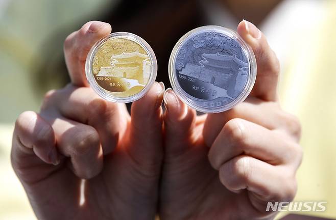 [서울=뉴시스] 정병혁 기자 = 8일 오전 서울 중구 숭례문 앞에서 열린 '국보 숭례문' 기념메달 디자인 공개 사진행사에서 모델이 기념메달을 선보이고 있다. 1398년(태조 7년)에 건축돼  625년을 맞은 숭례문을 기념해 만든 이 메달은 이날부터 금융기관과 온라인 쇼핑몰을 통해 선착순 예약접수를 시작한다. 2023.05.08. jhope@newsis.com