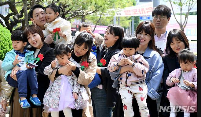 [광주=뉴시스] 변재훈 기자 = 광주 북구청 직장어린이집 원아와 부모들이 어버이날인 8일 광주 북구청 광장 앞에서 카네이션 전달 행사 뒤 기념촬영을 하고 있다. 2023.05.08. wisdom21@newsis.com