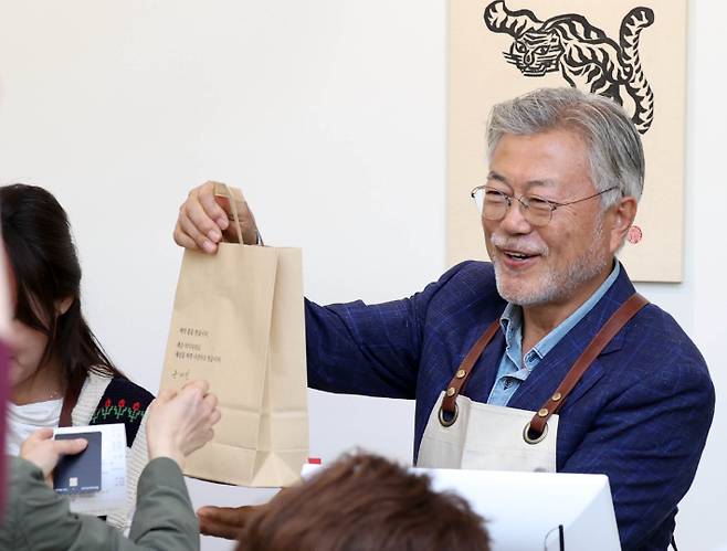 지난 4월 26일 문재인 전 대통령이 경남 양산시 하북면 자신의 책방 '평산책방'에서 계산 업무를 하며 책을 손님에게 건네고 있다. 연합뉴스