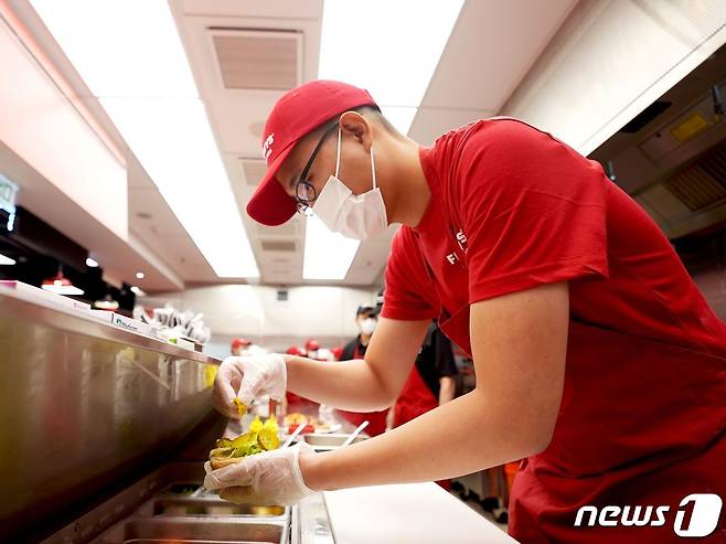 김동선 한화갤러리아 전략본부장이 지난달 말 홍콩 파이브가이즈 매장에서 다양한 종류의 토핑을 조합하는 방법을 연습하고 있다.(갤러리아 제공)