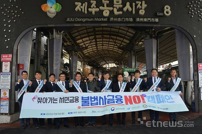 (오른쪽 다섯째부터) 이재연 서민금융진흥원장, 김원일 제주동문시장 상인회장,  김희현 제주도 정무부지사가 제주 동문 시장을 방문해 서민금융 캠페인을 펼치고 있다.