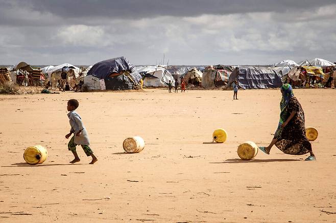 소말리아 난민 어린이들이 3월23일(현지시각) 아프리카 최대 난민촌 다다브 캠프에서 물통을 발로 굴리며 임시대피소로 가고 있다.