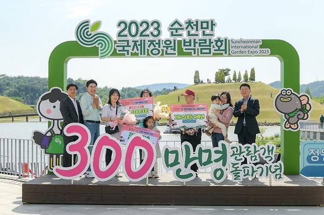 2023순천만국제정원박람회가 10일 개장 40일 만에 관람객 300만명을 넘어선 가운데 조직위원회 이사장을 맡고 있는 노관규 순천시장과 정병회 순천시의장이 국가정원 호수정원 나루터에 마련된 300만명 관람객 돌파 기념 포토존에서 300만 번째 입장객인 이정애씨와 가족들에게 '쉴랑게' 숙박권과 '정원드림호' 탑승권, 순천사랑상품권 50만원을 전달하고 기념촬영을 하고 있다. 사진=조직위 제공