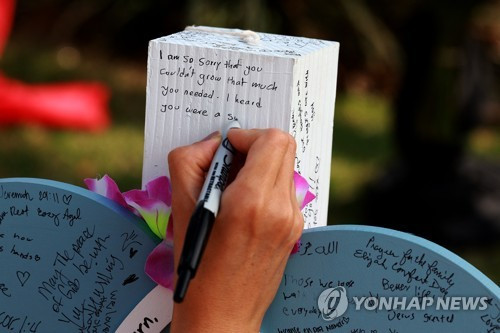 '총기난사' 사건 텍사스 쇼핑몰의 희생자 추모비에 애도의 글 적는 모습/ 앨런 AFP=연합뉴스