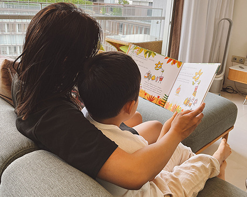 A worker from the Philippines reads a book to a child in Singapore. [Photo by a reader]