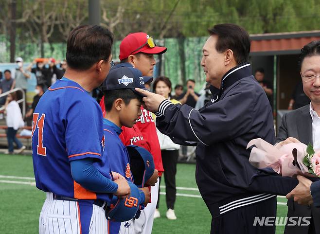 [서울=뉴시스] 전신 기자 = 윤석열 대통령이 14일 서울 용산어린이정원 내 야구장에서 열린 2023 대통령실 초청 전국 유소년 야구대회 결승 경기에 앞서 선수에게 기념모자를 전달하고 있다. (대통령실통신사진기자단) 2023.05.14. photo1006@newsis.com