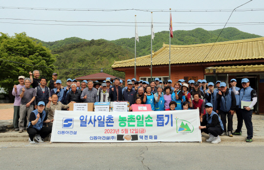 신동아건설 임직원 40여 명이 지난 12일 강원 영월 덕전마을을 찾아 농촌 일손돕기 봉사활동을 하고 마을 주민들과 기념촬영을 하고 있다. 신동아건설 제공