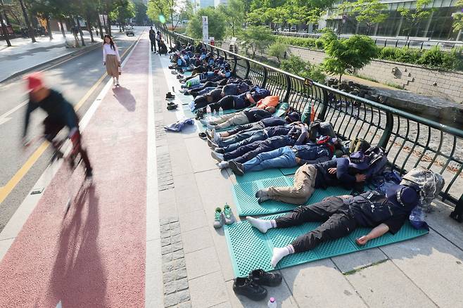 17일 오전 출근시간대 시민들이 서울 중구 청계광장에서 전날 밤 총파업 결의대회 후 노숙하고 있는 민주노총 건설노조원들을 지나치고 있다. 이날 건설노조를 포함한 민주노총은 오후 2시 숭례문 앞에 집결해 결의대회를 열고 삼각지역까지 행진할 예정이다. /연합뉴스