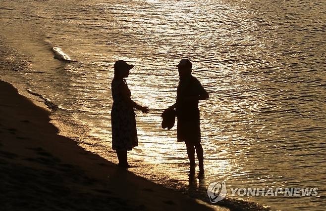 16일 낮 최고기온이 35.5도까지 올라가 한여름보다 더 더웠던 강원 강릉지역의 밤 기온이 30도 이하로 떨어지지 않은 가운데 안목해변에서 시민들이 바닷물에 발을 담근 채 무더위를 식히고 있다. [출처=연합뉴스]