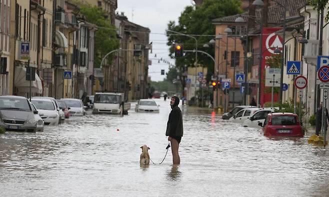 폭우로 물에 잠긴 이탈리아 북부 에밀리아-로마냐주 볼로냐에서 17일(현지시간) 한 주민이 반려견과 산책하고 있다. AP연합뉴스