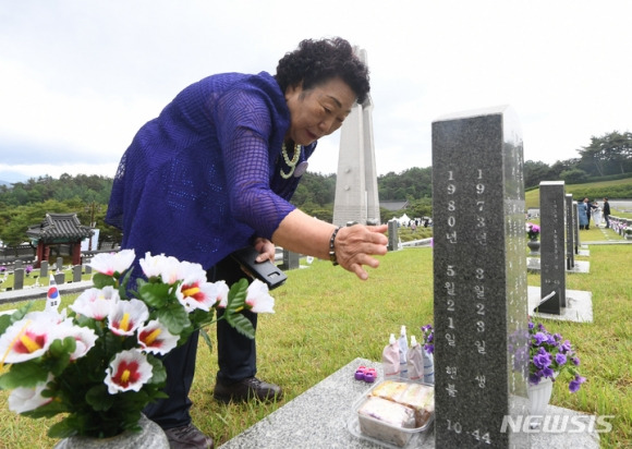 5·18행불자 이창현군 어머니 추모 - 당시 일곱 살 나이에 행방불명돼 지금까지 생사를 알지 못하는 이창현 군의 어머니 김말임 씨가 18일 오전 광주시 북구 운정동 국립 5·18민주묘지 행방불명자 묘역에 만들어진 아들의 가묘 묘비에 새겨진 영정(돌 사진)을 어루만지려  손을 뻗고 있다. 광주 뉴시스