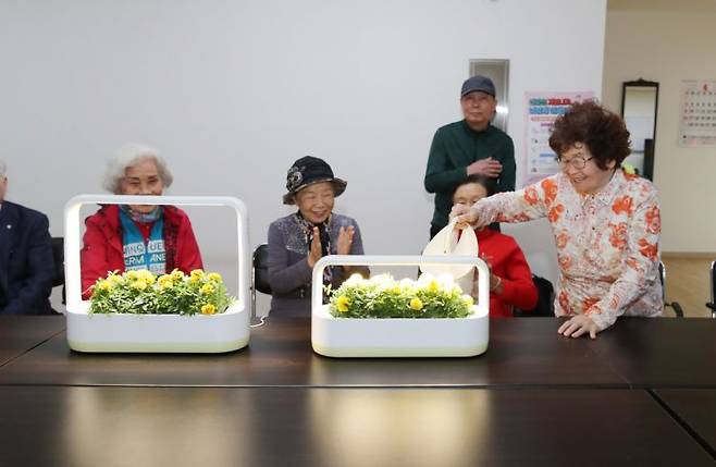 성동구 내 경로당에서 스마트 식물생활가전을 활용하여 반려식물에 물을 주고 있는 어르신