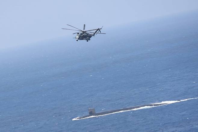 미국의 오하이오급 전략핵잠수함 메인함(SSBN 741)이 9일(현지시간) 필리핀해에서 임무 필수장비와 물자를 공급받기 위해 물 밖으로 부상해 항해하고 있다.  메인함의  위로 미 해병대의 슈퍼스탤리온(CH-53E) 수송헬기가 비행하고 있다. 출처 미 인도태평양사 트위터