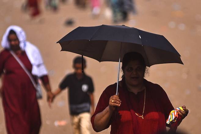 5월부터 아시아에 폭염이 이어지고 있는 가운데 지난 14일 인도 첸나이는 낮 온도가 40.7도에 이르렀다. 한 여성이 햇볕이 내리쬐는 거리를 우산을 들고 걷고 있다. 첸나이/EPA 연합뉴스