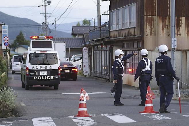 25일 일본 나가노에서 경찰관들이 총과 칼로 무장한 남성이 은신해 있는 건물 인근에서 경계를 서고 있다./AP 연합뉴스