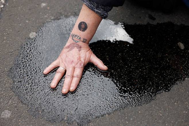 도로에 손 붙이기 독일 환경단체 ‘마지막 세대’의 한 활동가가 지난달 25일(현지시간) 수도 베를린에서 화석연료 사용 전면 중단을 요구하며 접착제로 손을 도로에 붙이고 있다. AFP연합뉴스