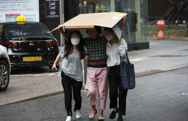 18일 서울 명동 거리에서 시민들이 내리는 비를 종이상자로 가리고 발걸음을 옮기고 있다. [연합]