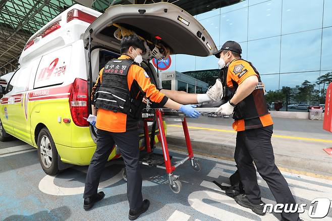 26일 오전 제주공항을 출발해 대구공항으로 향하던 아시아나 항공기에서 비행 중 문이 열리는 사고가 발생했다. 울산에서 열리는 제52회 전국소년체육대회에 참가하기 위해 비행기에 탑승했던 초·중학생 제주특별자치도 선수단 가운데 대구공항 도착 직후 고통을 호소하는 선수들을 119구조대가 병원으로 이송하기 위해 들것을 이용해 구급차로 옮기고 있다. 2023.5.26/뉴스1 ⓒ News1 공정식 기자