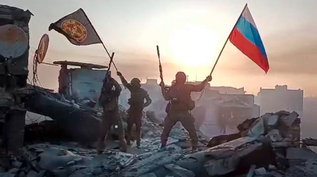 20일 러시아 민간용병 기업 바그너그룹이 공개한 사진에 바그너그룹 소속 군인들이 우크라이나 바흐무트의 손상된 건물 위에서 러시아 국기와 바그너 깃발을 흔들고 있다. 바흐무트=AP 뉴시스