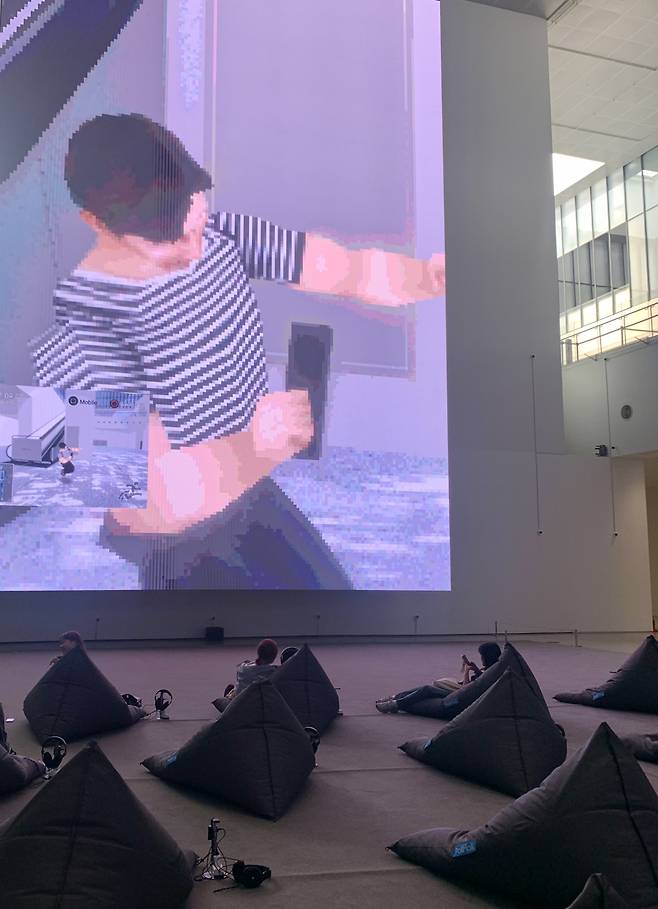 Visitors sit on bean bag chairs and watch Kim Heecheon's "Cutter III (2023)" at the "Game Society" exhibition. (No Kyung-min/The Korea Herald)
